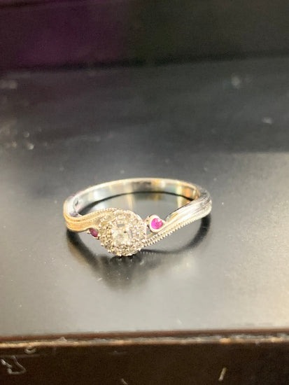 Silver ring with a heart-shaped gem on a reflective surface