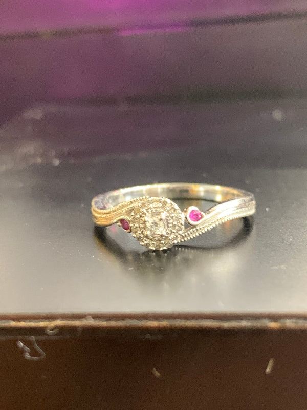Gold ring with a pink gemstone on a reflective surface